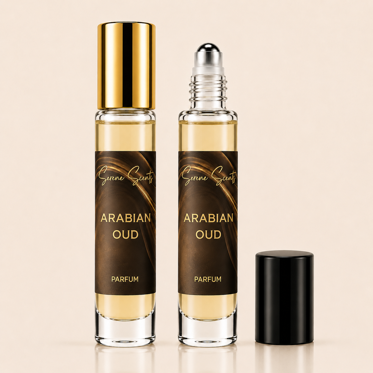 Two clear glass roller bottles of Arabian Oud perfume with dark brown labels and gold lettering, one with a gold cap and one with a silver roller top, shown on a light beige background with a black cap placed beside them.