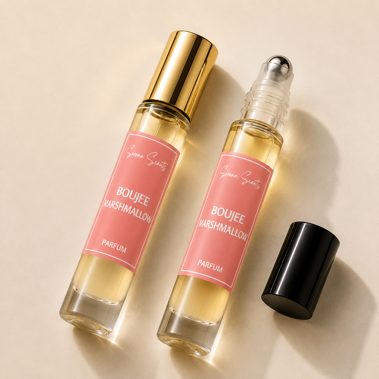 Two clear glass rollerball perfume bottles with pink labels and gold-toned caps, shown on a warm beige background. One bottle has a gold cap and the other has a clear cap with a black roller ball, both labeled 'Boujee Marshmallow' by the brand 'Scent of Days'.
