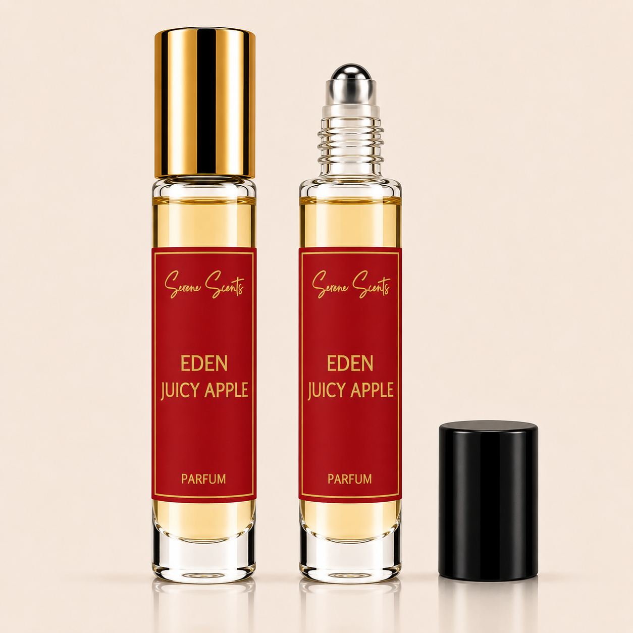 Two clear glass rollerball perfume bottles with red labels reading Eden Juicy Apple Parfum, one with a gold cap and one with a black cap, on a light beige background.