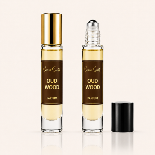 Two clear glass perfume roller bottles labeled 'Oud Wood Parfum' by Scenic Scents, one with a gold cap and one with a black cap, shown on a light beige background.