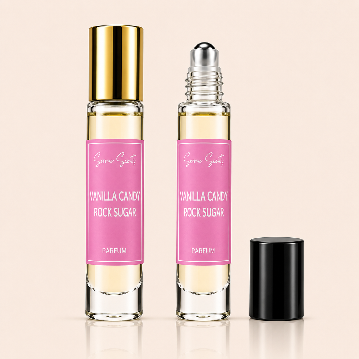 Two clear glass perfume roller bottles with pink labels reading 'Vanilla Candy Rock Sugar' and 'Parfum' are shown on a light beige background. One bottle has a gold cap and is upright, while the other has a silver roller top and is open, with a black cap placed beside it.
