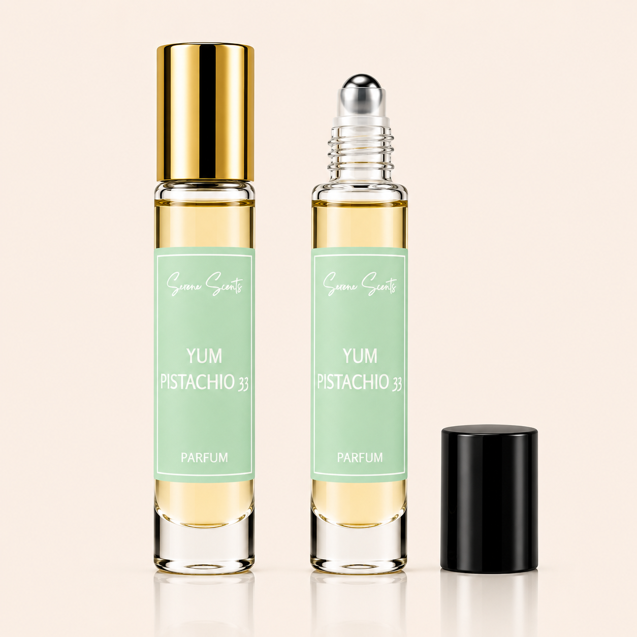 Two clear glass perfume roller bottles with pale mint green labels and pale yellow liquid, shown on a light beige background. One bottle has a shiny gold cap and stands upright, while the other has a clear cap and silver roller ball, with a separate black cap placed beside it.